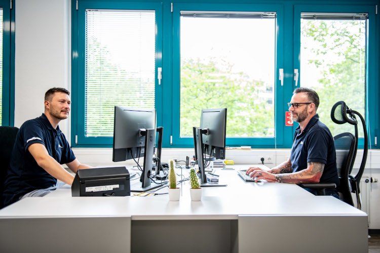 JTL-Mitarbeiter sitzen sich im Büro gegenüber