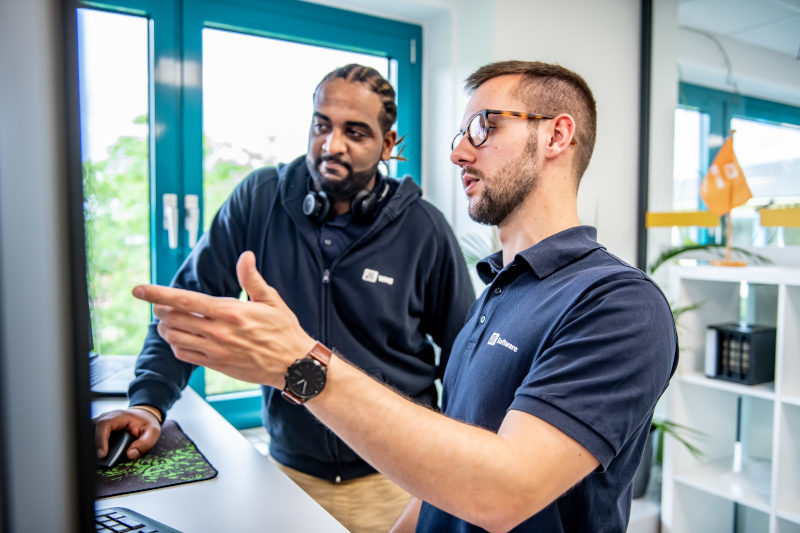 Zwei JTL-Mitarbeiter diskutieren am PC über ein Projekt