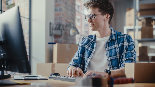 Junger Mann mit Brille am PC im Lager
