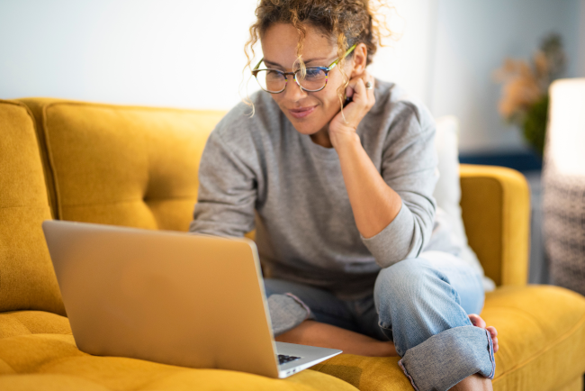 Frau am Laptop auf gelber Couch