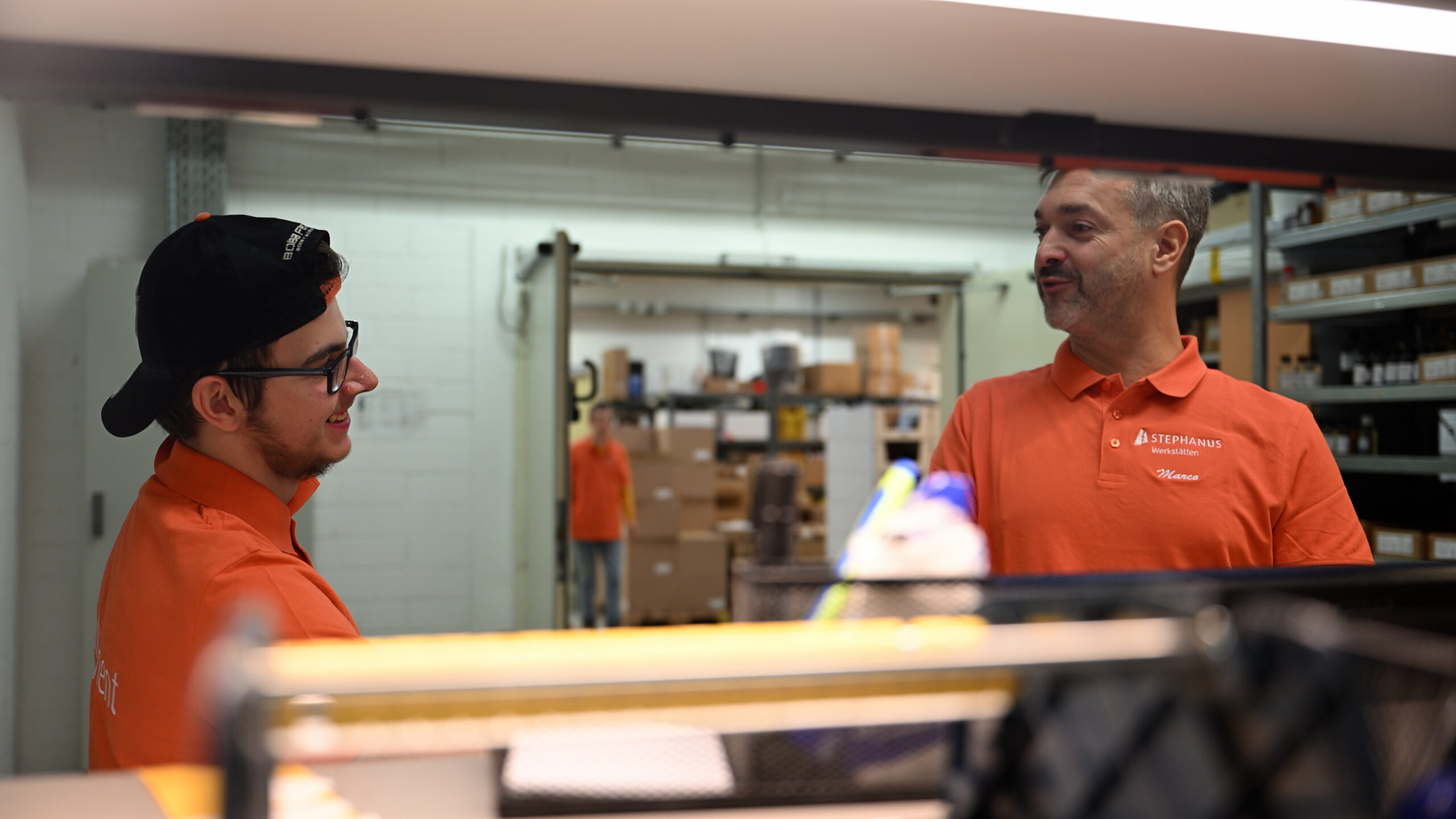 Ein Gruppenleiter und ein Beschäftigter der Stephanus-Werkstätten führen glücklich ein Gespräch.