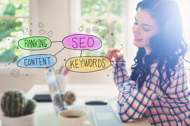 Junge Frau in kariertem Hemd am Laptop mit SEO-Keywords