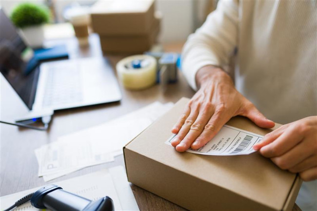Versandlabel wird auf Paket geklebt