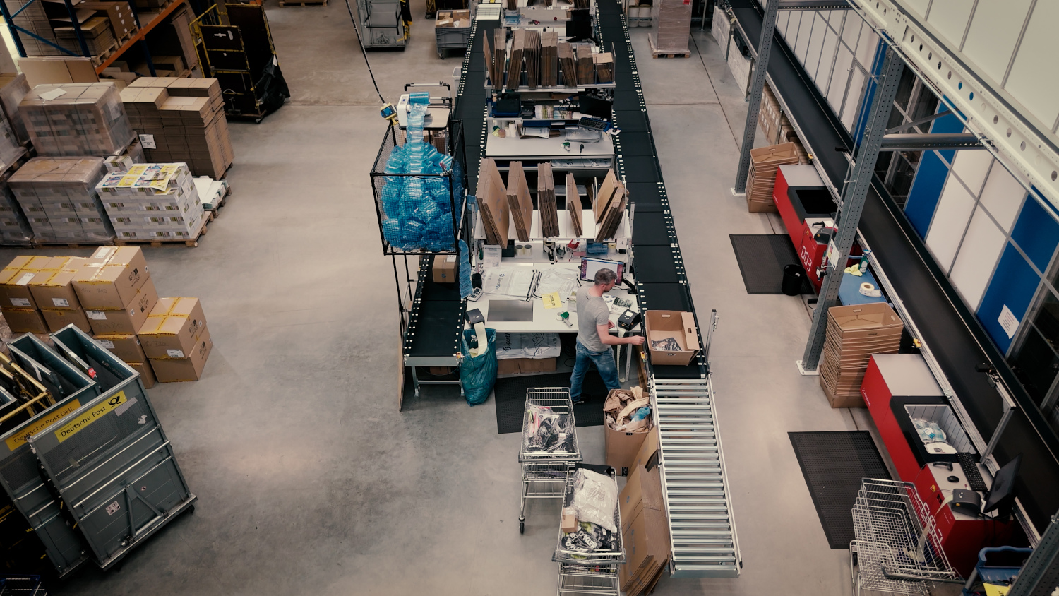 Mann packt in großer Lagerhalle Paket