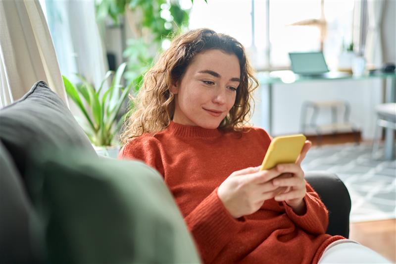 Junge Frau mit Handy zu Hause