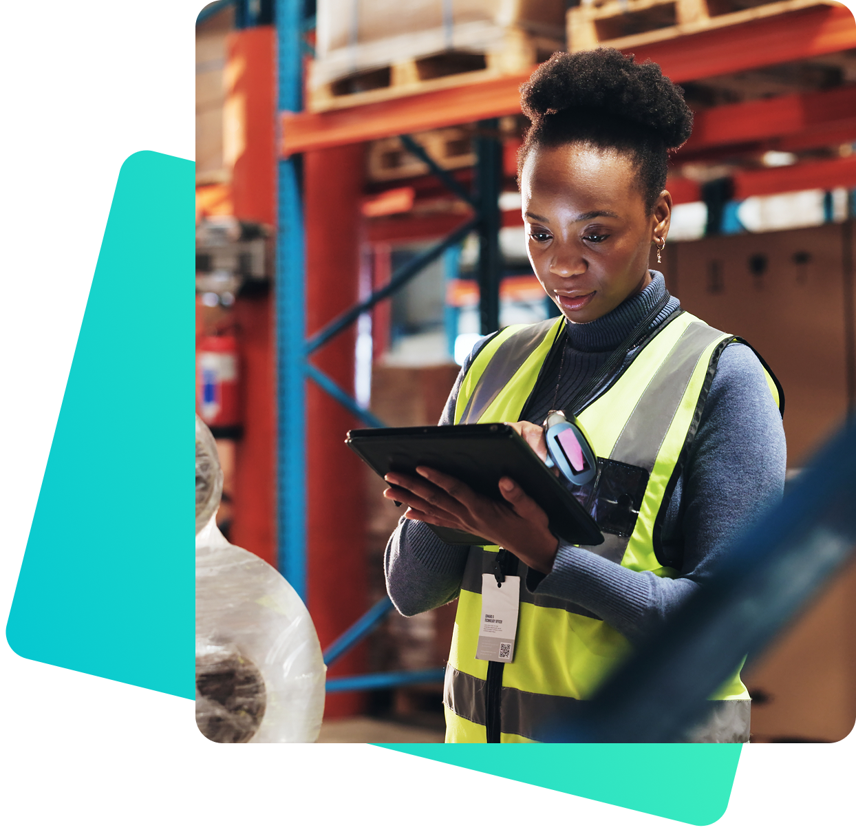 Eine Frau in gelber Warnweste steht in einem Lager zwischen Regalen mit Kartons und bedient ein Tablet. Sie trägt ein Namensschild und ein tragbares Scannergerät.