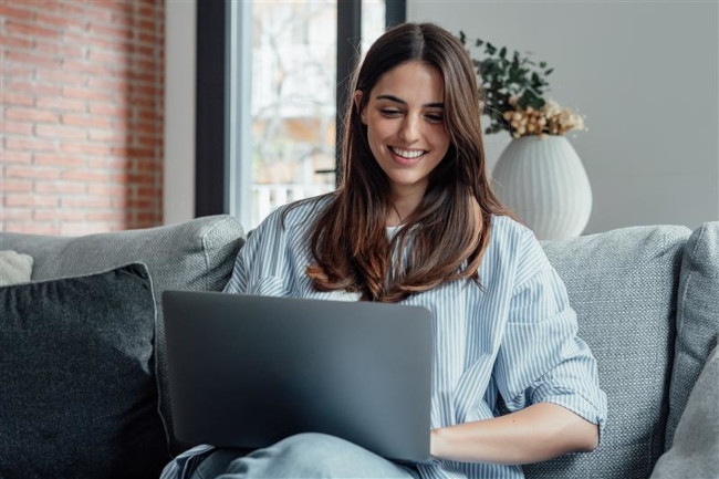 Junge Frau auf der Couch mit Laptop