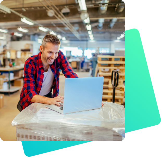 Lagerarbeiter nutzt Laptop auf verpackter Palette zur Steuerung und Automatisierung von Logistikprozessen im Lager
