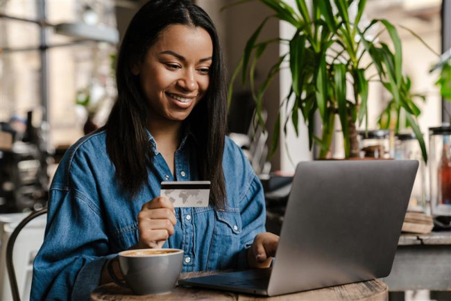 junge Frau im Cafe mit Kreditkarte am Laptop